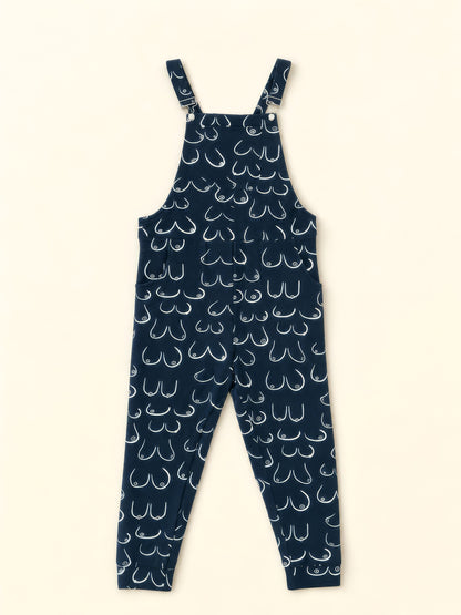 A pair of navy blue overalls with an all-over white hand-drawn style boob pattern, shown flat against a light cream background.