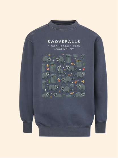 A navy blue crewneck sweatshirt featuring a graphic print of raccoons in trash cans with the text 'SWOVERALLS "Trash Pandas" 2026 Brooklyn, NY' on the chest, displayed against a solid cream background.