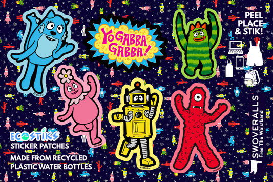 A flat lay of colorful sticker patches on a dark patterned background. The patches include blue, pink, green, yellow, and red cartoon characters, with text reading 'YoGabba! YoGabbas'.