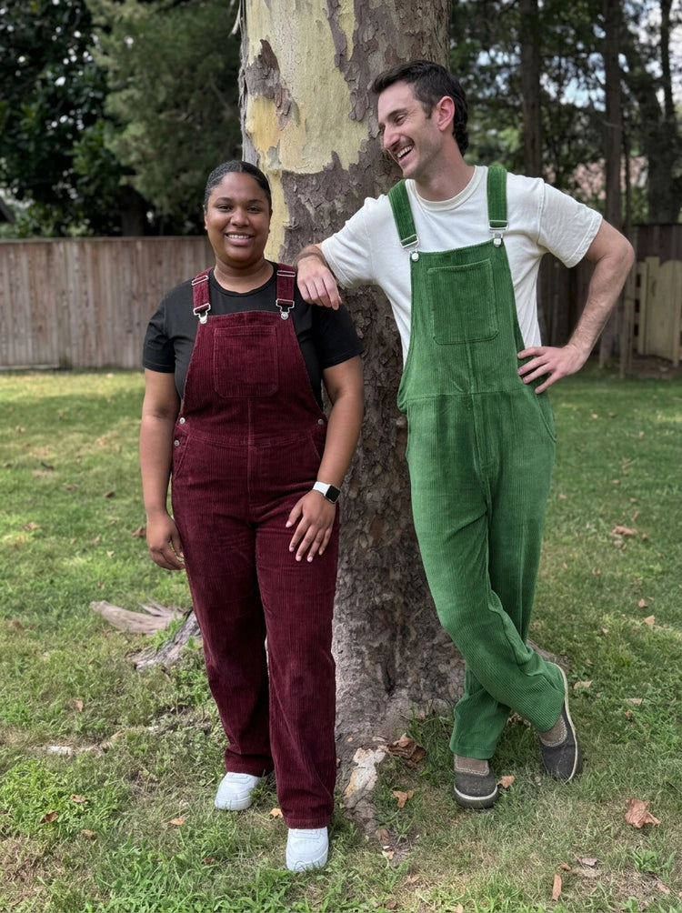 Two people by a tree wearing Bordeaux and Forest Green Corduroy Swoveralls
