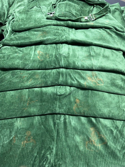 Stack of Perfectly Imperfect Forest Green corduroy Swoveralls showing light rust-colored marks on the fabric