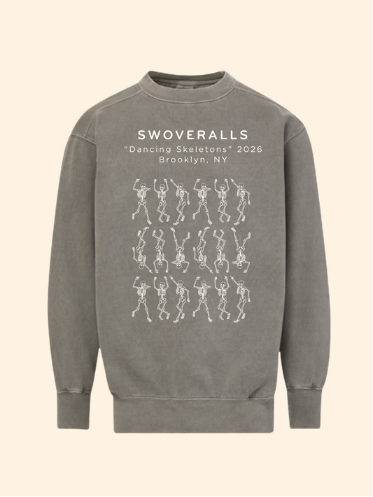 A gray crewneck sweatshirt featuring white printed text that reads 'SWOVERALLS "Dancing Skeletons" 2026 Brooklyn, NY' above a grid of white skeleton dancers, shown on a solid cream background.