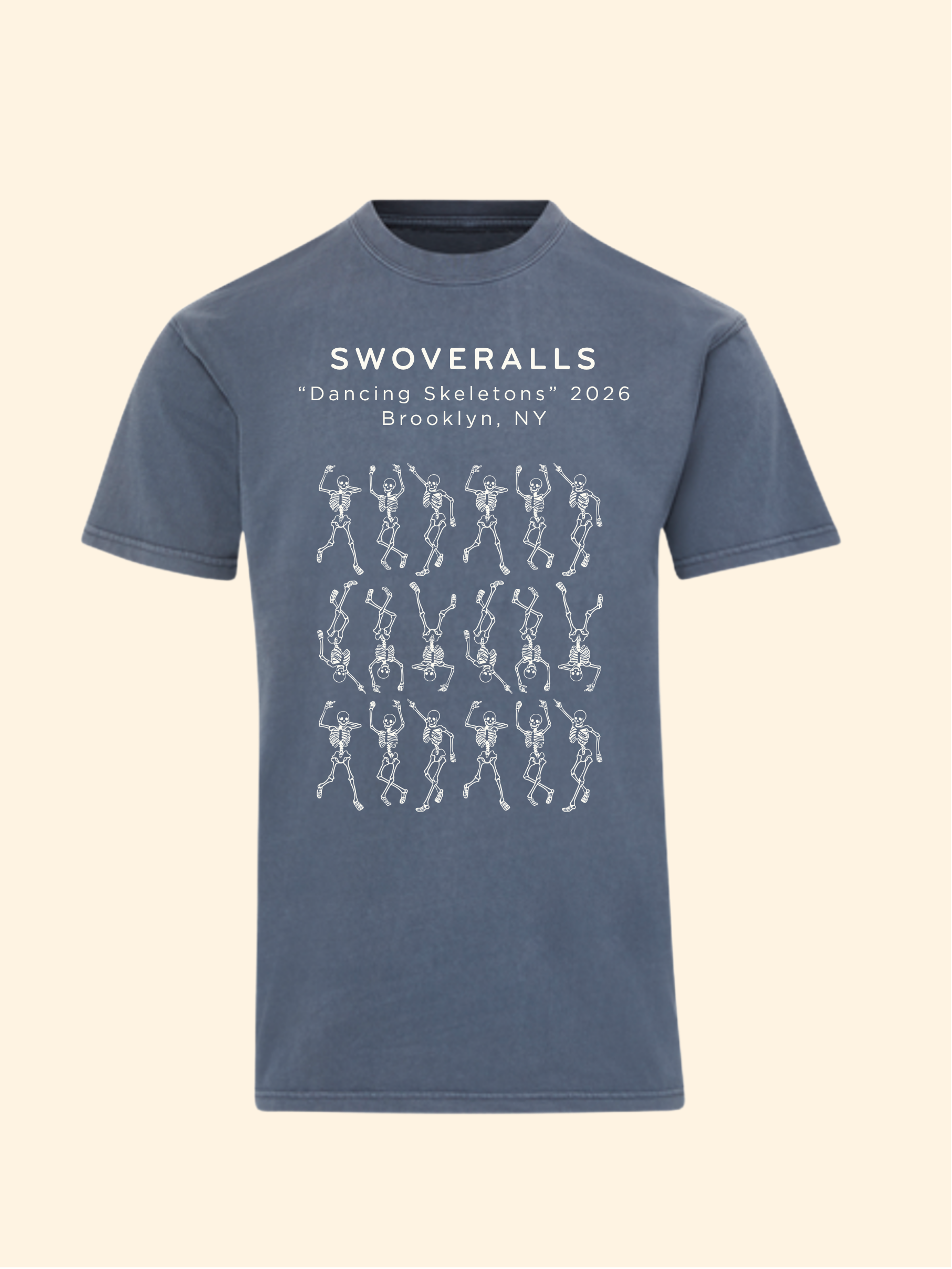A slate blue short-sleeve t-shirt with a white graphic print on the front. The print features the text 'SWOVERALLS "Dancing Skeletons" 2026 Brooklyn, NY' above a grid of white line-drawn skeleton figures, shown against a solid pale cream background.